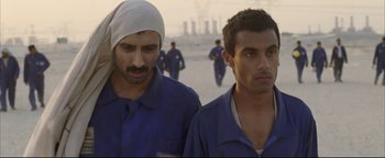 Movie still from “Syriana” (2005), directed by Stephen Gaghan – A couple of men standing next to each other on a beach; Close Up shot, Over the shoulder angle