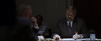 Movie still from “Syriana” (2005), directed by Stephen Gaghan – Two men sitting at a table in front of each other; Medium shot, Over the shoulder angle