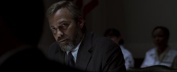 Movie still from “Syriana” (2005), directed by Stephen Gaghan – A person wearing a suit and tie; Close Up shot, Over the shoulder angle