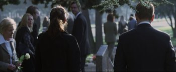 Movie still from “Syriana” (2005), directed by Stephen Gaghan – A group of people in suits standing around a grave; Medium shot, Over the shoulder angle