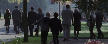 Movie still from “Syriana” (2005), directed by Stephen Gaghan – A group of people walking down a sidewalk; Wide shot, Over the shoulder angle