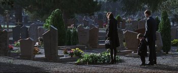 Movie still from “Syriana” (2005), directed by Stephen Gaghan – A woman standing in front of a grave with flowers; Wide shot, High angle