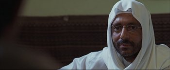 Movie still from “Syriana” (2005), directed by Stephen Gaghan – A man in a white shirt and a head covering; Close Up shot, Over the shoulder angle