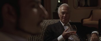 Movie still from “Syriana” (2005), directed by Stephen Gaghan – An older man wearing a suit talking to someone; Close Up shot, Over the shoulder angle