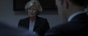 Movie still from “Syriana” (2005), directed by Stephen Gaghan – A woman wearing a suit and a button up shirt; Close Up shot, Over the shoulder angle