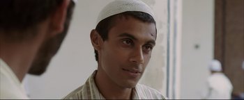 Movie still from “Syriana” (2005), directed by Stephen Gaghan – A man wearing a white hat and a white shirt; Close Up shot, High angle
