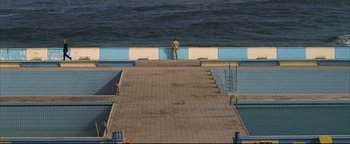 Movie still from “Syriana” (2005), directed by Stephen Gaghan – A man standing on the edge of a swimming pool; Extreme Wide shot, High angle