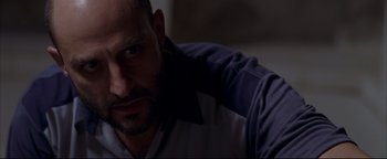 Movie still from “Syriana” (2005), directed by Stephen Gaghan – A man's face in a dark room; Close Up shot, Low angle