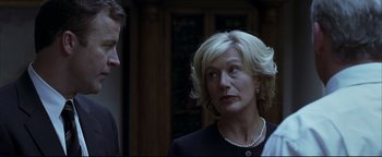 Movie still from “Syriana” (2005), directed by Stephen Gaghan – A woman with blonde hair wearing a black jacket; Close Up shot, Over the shoulder angle