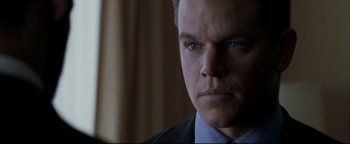 Movie still from “Syriana” (2005), directed by Stephen Gaghan – A person wearing a suit and tie; Close Up shot, Over the shoulder angle