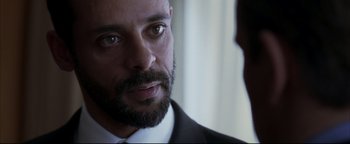 Movie still from “Syriana” (2005), directed by Stephen Gaghan – A person wearing a suit and a tie; Close Up shot, Over the shoulder angle