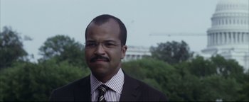 Movie still from “Syriana” (2005), directed by Stephen Gaghan – A person wearing a suit and tie; Close Up shot, Over the shoulder angle