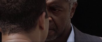 Movie still from “Syriana” (2005), directed by Stephen Gaghan – A man looking at another man's reflection in a mirror; Close Up shot, Over the shoulder angle