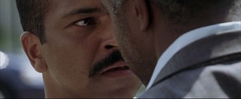 Movie still from “Syriana” (2005), directed by Stephen Gaghan – A man with a mustache looking at another man; Extreme Close Up shot, Over the shoulder angle