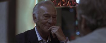 Movie still from “Syriana” (2005), directed by Stephen Gaghan – An older man is sitting in front of a window; Close Up shot, Over the shoulder angle