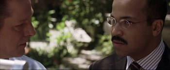 Movie still from “Syriana” (2005), directed by Stephen Gaghan – A person wearing glasses with trees in the background; Close Up shot, Over the shoulder angle