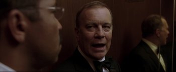 Movie still from “Syriana” (2005), directed by Stephen Gaghan – An older man in a suit and bow tie; Close Up shot, Low angle