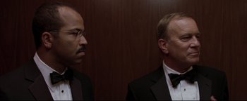 Movie still from “Syriana” (2005), directed by Stephen Gaghan – A man in a suit and tie standing next to another man in a suit and tie; Close Up shot, Over the shoulder angle