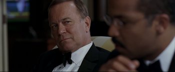 Movie still from “Syriana” (2005), directed by Stephen Gaghan – An older man in a tuxedo and a younger man in a suit; Close Up shot, Over the shoulder angle