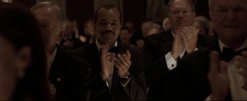 Movie still from “Syriana” (2005), directed by Stephen Gaghan – A man clapping his hands in front of a crowd; Medium shot, Low angle