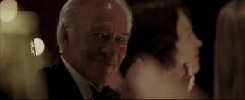 Movie still from “Syriana” (2005), directed by Stephen Gaghan – An older man wearing a suit and bow tie; Close Up shot, Low angle