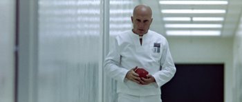 Movie still from “THX 1138” (1971), directed by George Lucas – A man in a lab coat holding an apple in his hands; Medium shot, Low angle