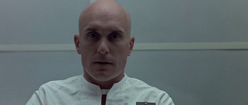 Movie still from “THX 1138” (1971), directed by George Lucas – A man with bald head wearing a white shirt; Close Up shot, Low angle