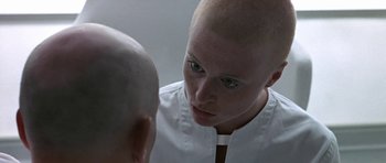 Movie still from “THX 1138” (1971), directed by George Lucas – A woman looking into a mirror with a bald head; Close Up shot, Over the shoulder angle