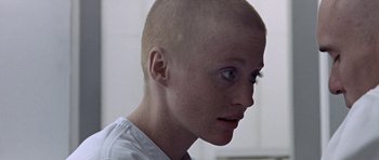 Movie still from “THX 1138” (1971), directed by George Lucas – A woman with a shaved head looking into the distance; Close Up shot, High angle