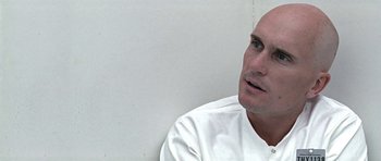 Movie still from “THX 1138” (1971), directed by George Lucas – A man in a white shirt is sitting in front of a white wall; Close Up shot, Over the shoulder angle