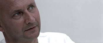 Movie still from “THX 1138” (1971), directed by George Lucas – A man's face in a white shirt; Close Up shot, Over the shoulder angle