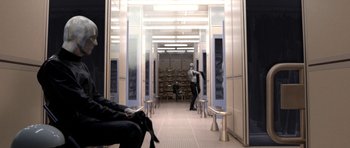 Movie still from “THX 1138” (1971), directed by George Lucas – A man is standing in a room with chairs and tables; Wide shot, Over the shoulder angle