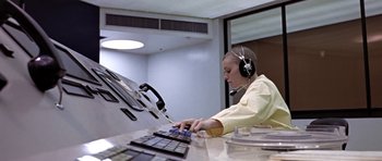 Movie still from “THX 1138” (1971), directed by George Lucas – A person wearing headphones and using a computer keyboard; Medium shot, Low angle