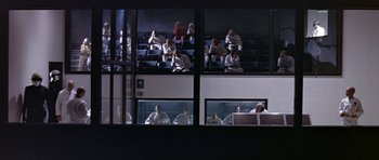 Movie still from “THX 1138” (1971), directed by George Lucas – A group of people sitting in a room with windows open; Extreme Wide shot, Low angle
