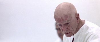 Movie still from “THX 1138” (1971), directed by George Lucas – An old man with a bald head looking down at the ground; Close Up shot, Low angle