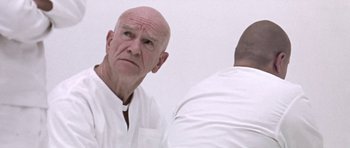 Movie still from “THX 1138” (1971), directed by George Lucas – An older man looking at a younger man in front of a mirror; Close Up shot, Low angle