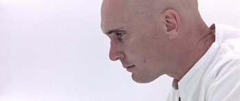 Movie still from “THX 1138” (1971), directed by George Lucas – A man with bald head looking to the side; Close Up shot, Low angle