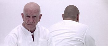 Movie still from “THX 1138” (1971), directed by George Lucas – A man in a white shirt is looking at another man in a white shirt; Close Up shot, Over the shoulder angle