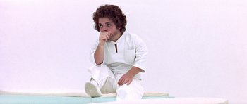 Movie still from “THX 1138” (1971), directed by George Lucas – A person sitting on the ground with his hand under his chin; Medium shot, High angle