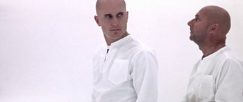 Movie still from “THX 1138” (1971), directed by George Lucas – A bald man in a white shirt is looking at the camera; Close Up shot, Low angle