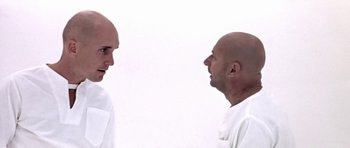 Movie still from “THX 1138” (1971), directed by George Lucas – Two bald men facing each other in front of a white wall; Close Up shot, Low angle