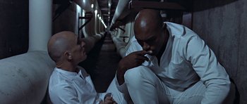 Movie still from “THX 1138” (1971), directed by George Lucas – Two men sitting on the floor of a train; Medium shot, High angle