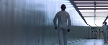 Movie still from “THX 1138” (1971), directed by George Lucas – A man in a white suit is walking in a tunnel; Wide shot, Low angle