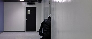 Movie still from “THX 1138” (1971), directed by George Lucas – A person with a backpack walking down a hall way; Wide shot, High angle