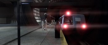 Movie still from “THX 1138” (1971), directed by George Lucas – Two men are standing on the platform waiting for a train to arrive; Extreme Wide shot, High angle