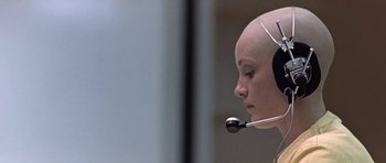 Movie still from “THX 1138” (1971), directed by George Lucas – A person with a headset on is looking at something; Close Up shot, Low angle