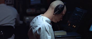 Movie still from “THX 1138” (1971), directed by George Lucas – A bald man wearing headphones and a white shirt; Close Up shot, High angle