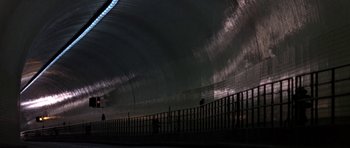 Movie still from “THX 1138” (1971), directed by George Lucas – People are walking on a sidewalk near a tunnel; Extreme Wide shot, Low angle