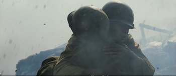 Movie still from “Tae Guk Gi: The Brotherhood of War” (2004), directed by Kang Je-kyu – Two men in military fatigues hug in the air; Close Up shot, Low angle