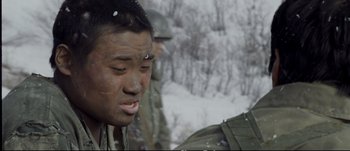 Movie still from “Tae Guk Gi: The Brotherhood of War” (2004), directed by Kang Je-kyu – A man in a military fatigues is looking into the distance; Close Up shot, Over the shoulder angle